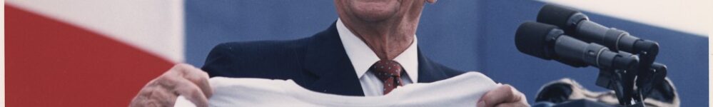 Man holding "The Gipper" jersey, smiling.
