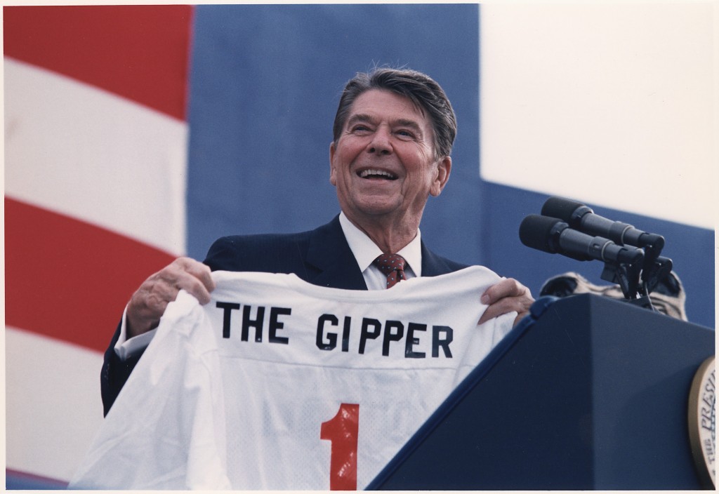 Man holding "The Gipper" jersey, smiling.